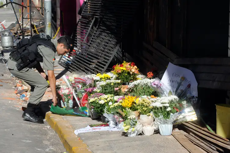 Santa Maria (RS) - Um ano do incêncio na Boate Kiss durante show na madrugada do dia 27 de janeiro de 2013. A pedido de moradores, policial militar deposita flores em frente a boate  (Wilson Dias/Agência Brasil)