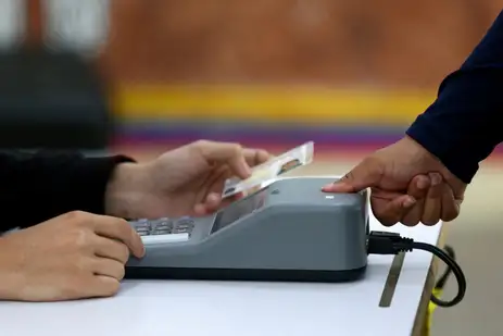 A woman is checked with a fingerprint identity registration device at a polling station in the Liceo Andres Bello during Venezuela's presidential election, in Caracas, Venezuela, July 28, 2024. REUTERS/Fausto Torrealba